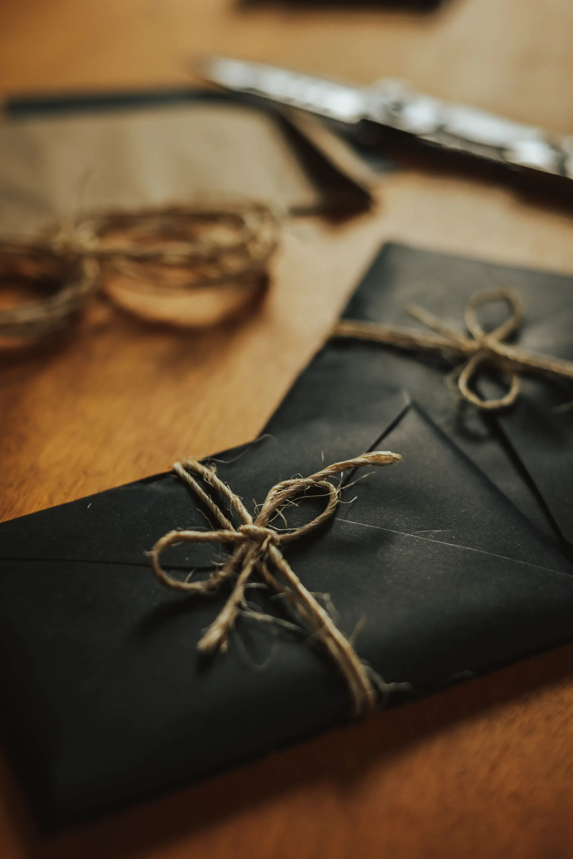 Matte black envelopes tied with twine on warm wood