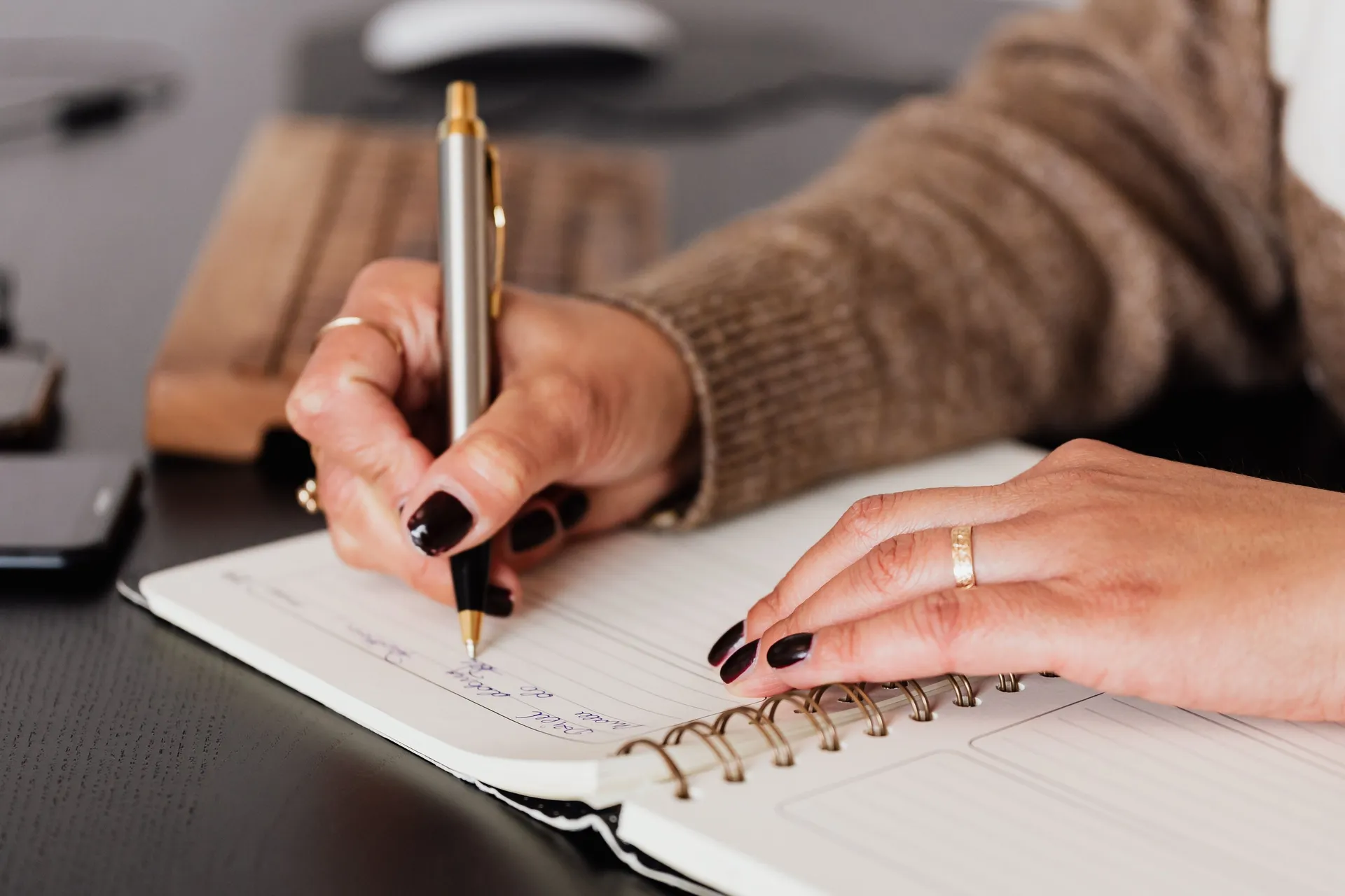 Hands writing in a spiral notebook